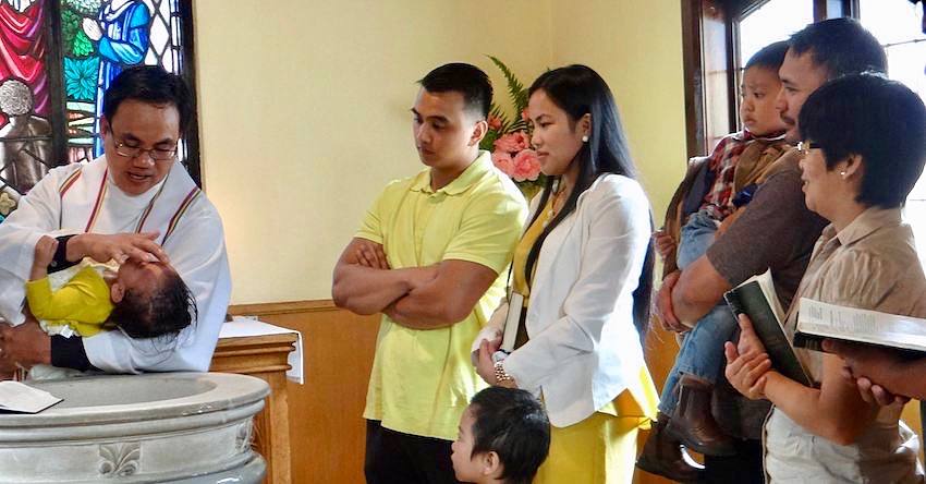 Baby getting baptised with family watching